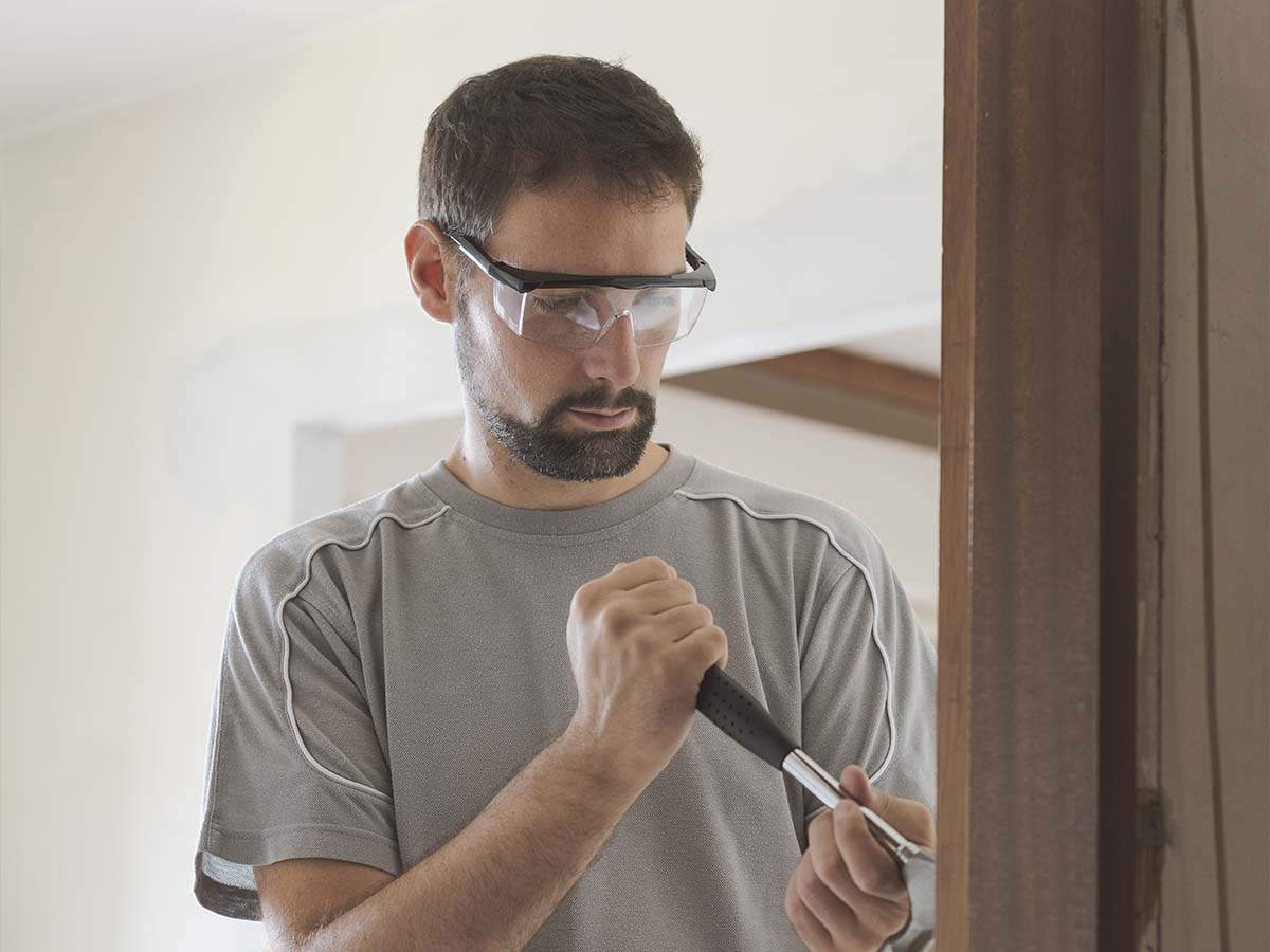 Man wearing goggles working on house renovation